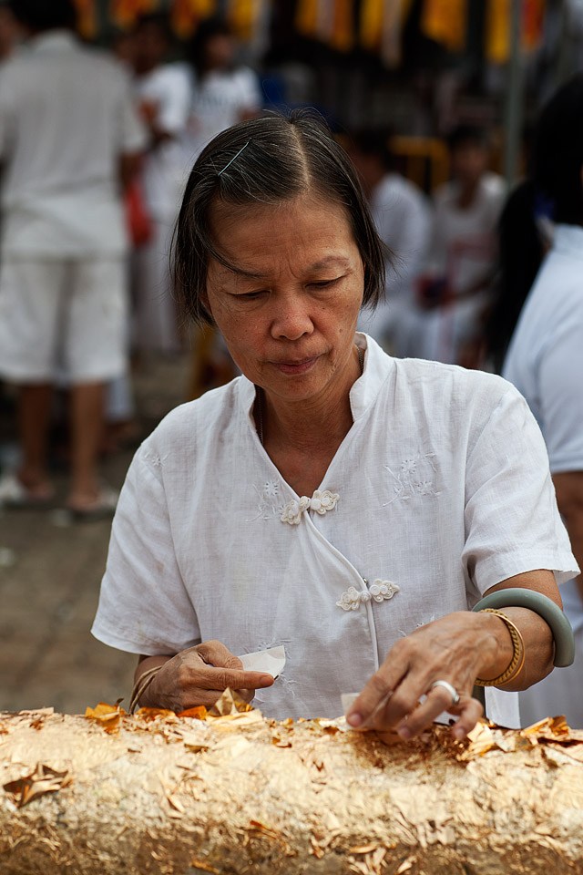 Devotee applying gold leaf.