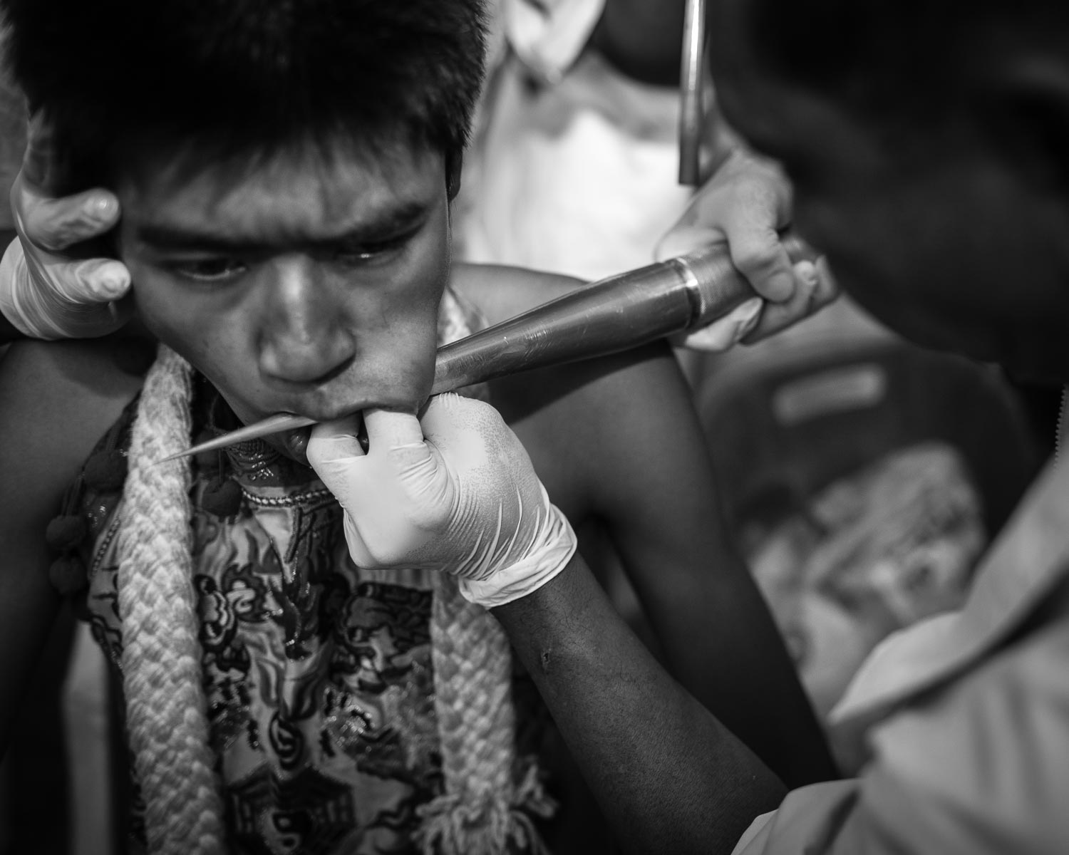 man getting cheek pierced during phuket vegetarian festival