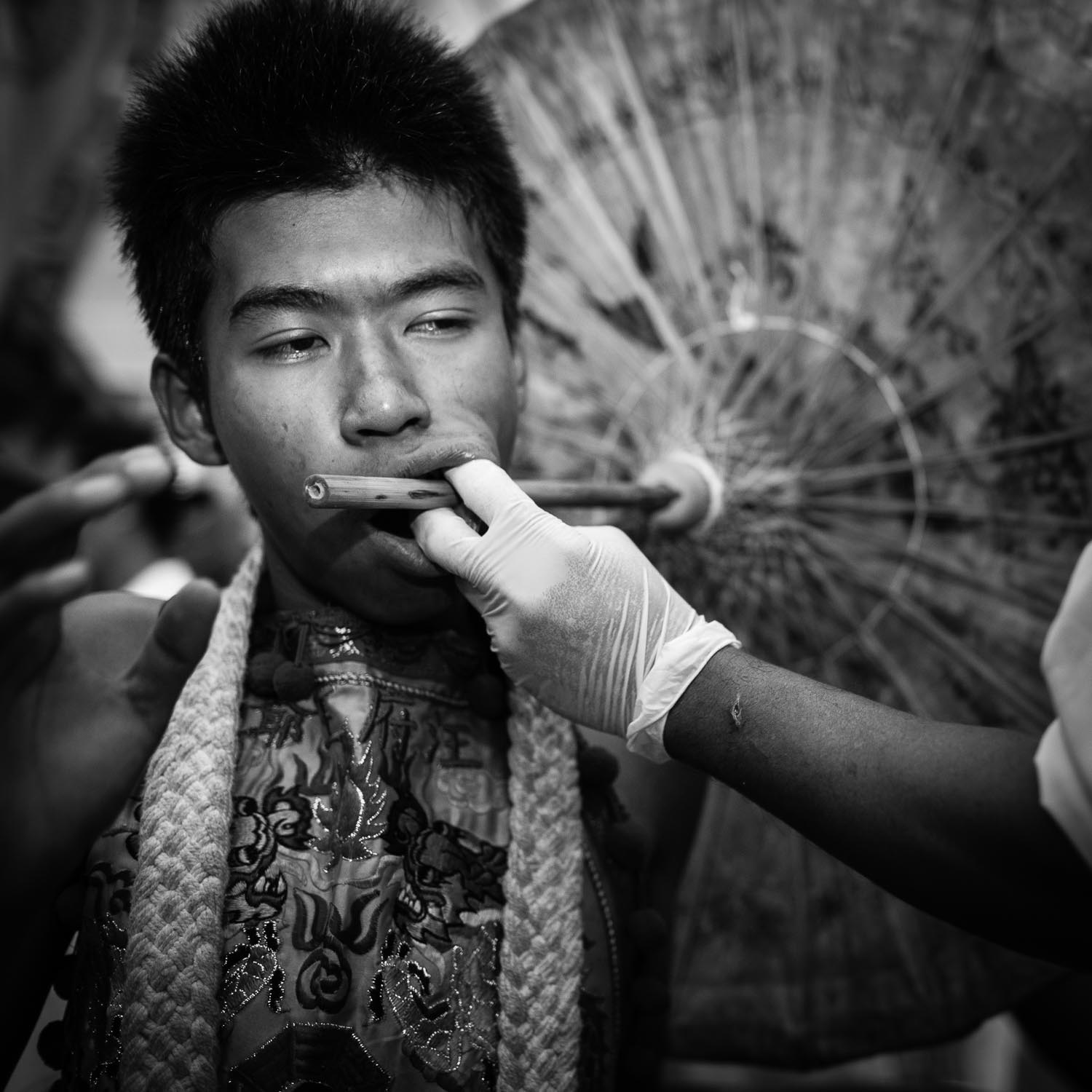 man pierced cheek umbrella phuket vegetarian festival